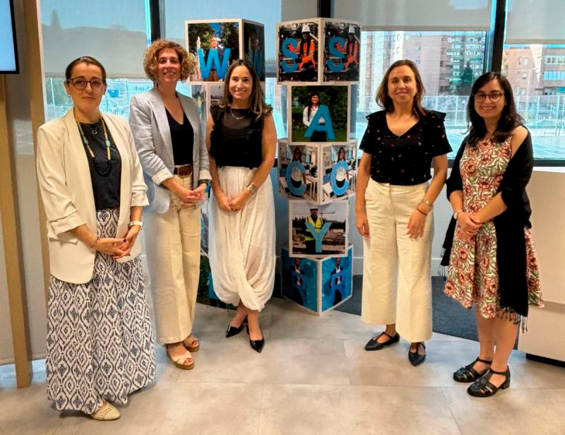 Cinco representantes de Sacyr y Fundación Descúbreme posan junto a una instalación visual en las oficinas de Sacyr en Madrid.